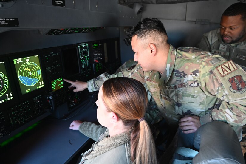 An airman points to a computer screen as others watch.