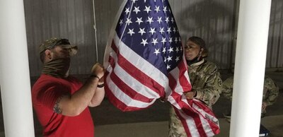 Man and woman lower American flag.