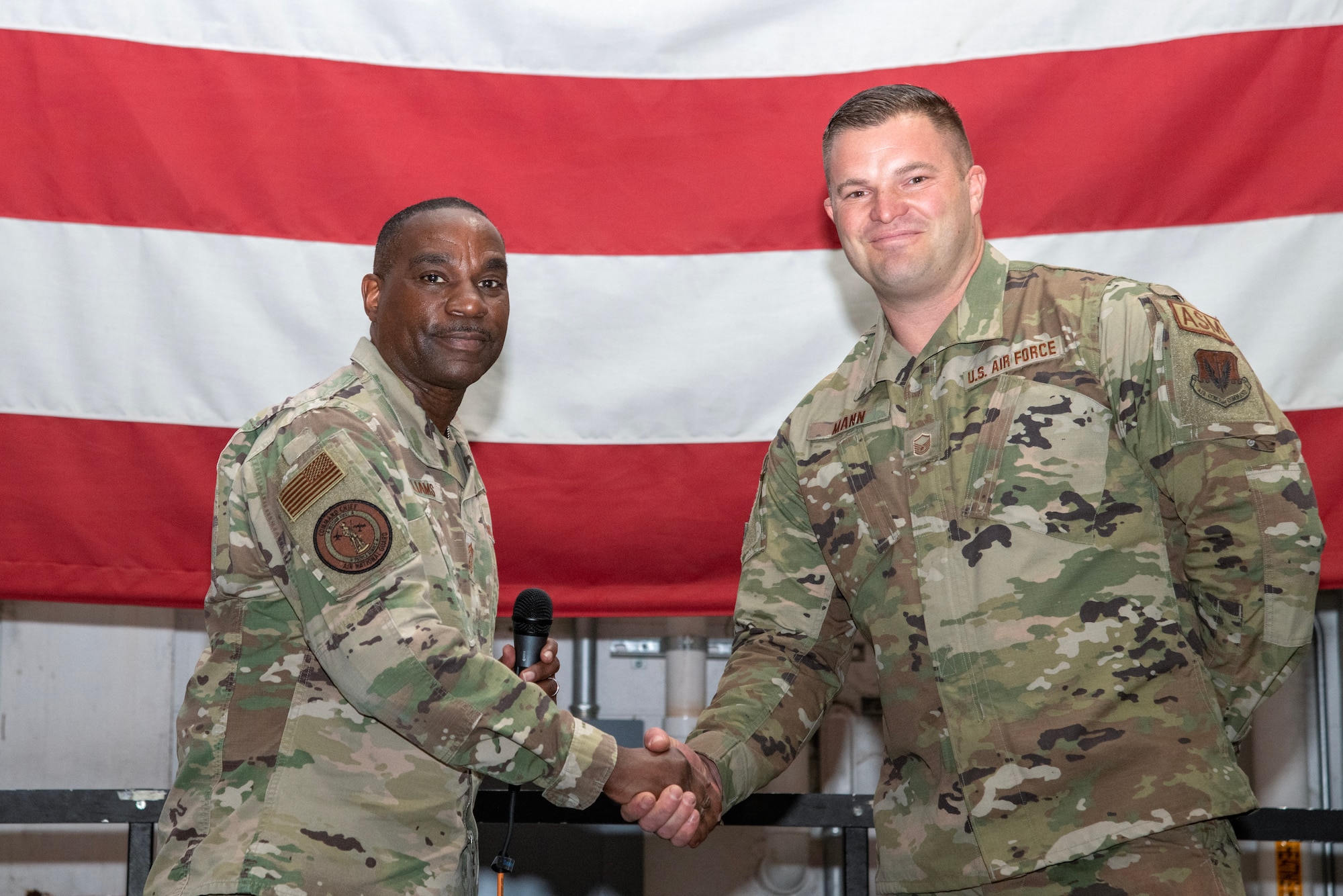 A photo of Chief Master Sgt. Maurice L. Williams coining Master Sgt. Ryan Mann.
