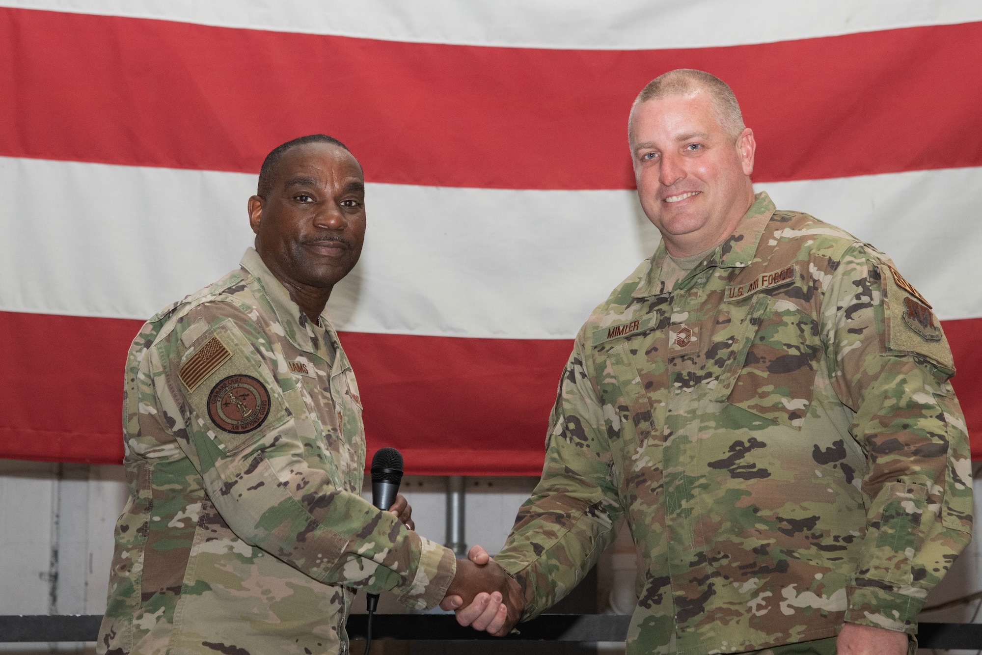 A photo of Chief Master Sgt. Maurice L. Williams coining Senior Master Sgt. Michael Mimler.