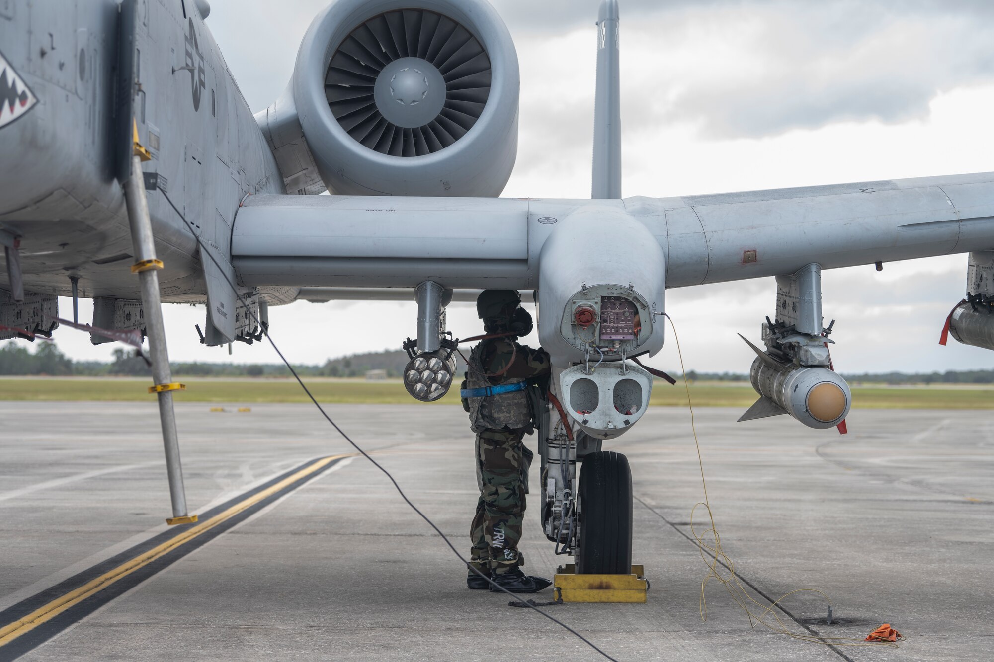 A photo of a person standing under the wing of an A-10C Thunderbolt II.
