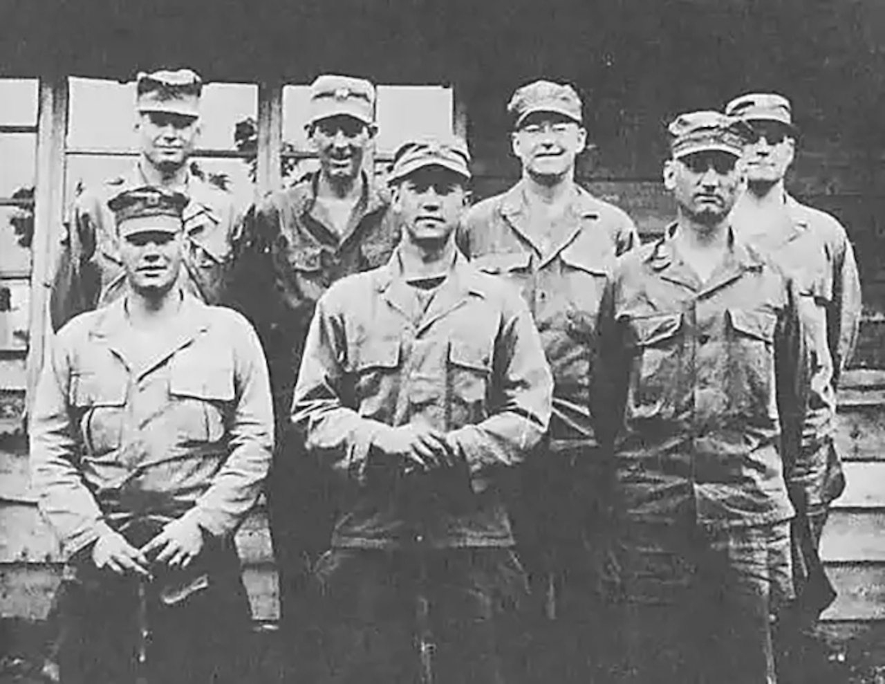 Seven men stand in two rows to pose for a photo.