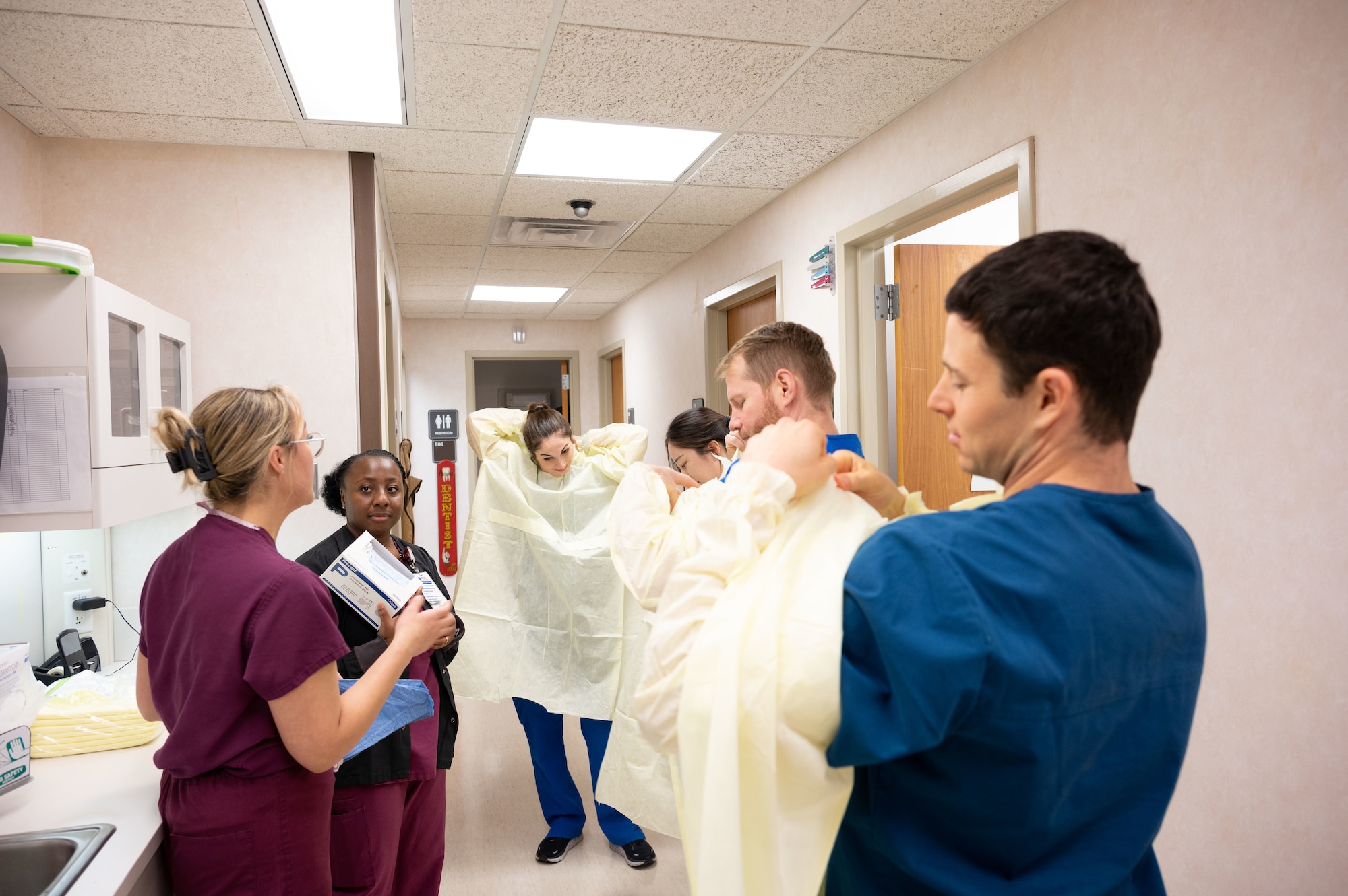 U.S. Air Force Staff Sgt. Tamaya Dash, second from left, 436th Medical Group non-commissioned officer in charge of preventive dentistry, and Senior Airman Kayla Dia, 436th Dental Flight prophylaxis technician, issue personal protective equipment to University of Pennsylvania students during the Health Professions Scholarship Program tour at Dover Air Force Base, Delaware, Nov. 16, 2023. The visit was the first time students shadowed Air Force doctors, the busiest in the Air Mobility Command. (U.S. Air Force photo by Airman 1st Class Dieondiere Jefferies)