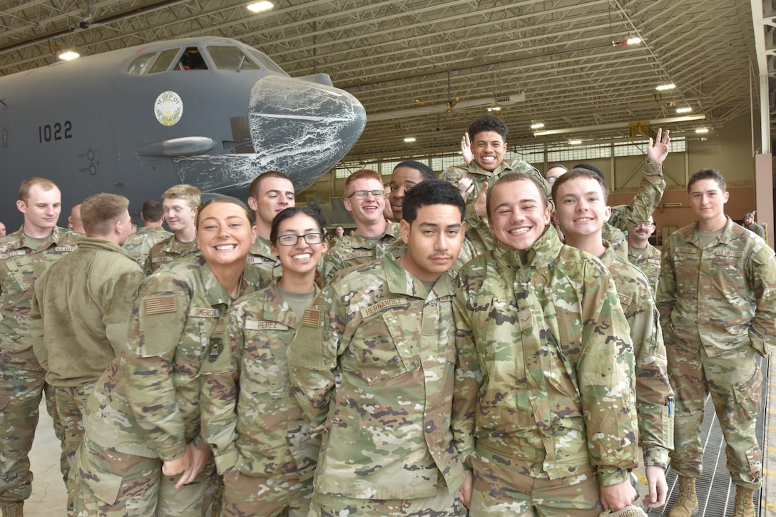 A group of Airmen smile at the camera inside a hangar.