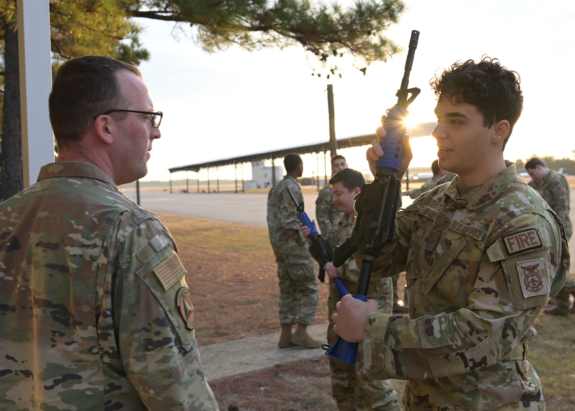 Two Airmen inspect a training rifle.