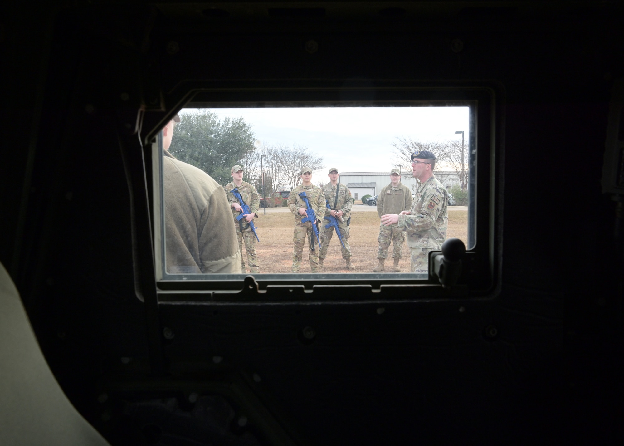 A group of Airmen are seen through the window of a vehicle.
