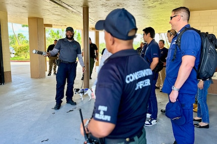 Officer Tomas Mantanona, a canine handler with the U.S. Department of Agriculture, gives a demonstration with canine Spot on snake identification with participants of the U.S. Coast Guard Forces Micronesia/Sector Guam hosted second annual Industry Day on Nov. 20, 2023, in Guam. Following the success of the inaugural session in 2022, this event further strengthened the collaboration between the U.S. Coast Guard and the maritime industry. The day's agenda included insightful presentations and discussions led by U.S. Coast Guard officials and industry experts. Topics ranged from domestic vessel inspection and maritime cybersecurity to modernization updates from the Port of Guam. This Industry Day is significant for the U.S. Coast Guard and the maritime industry. It provides a unique platform for a mutual exchange of ideas and challenges, helping to build a stronger, more informed maritime community. (U.S. Coast Guard photo by Chief Warrant Officer Sara Muir)