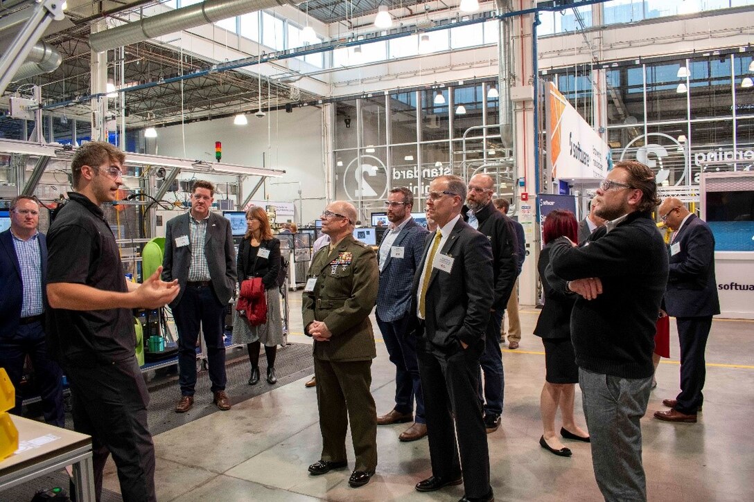 People gather to listen to a speaker on a factory floor.