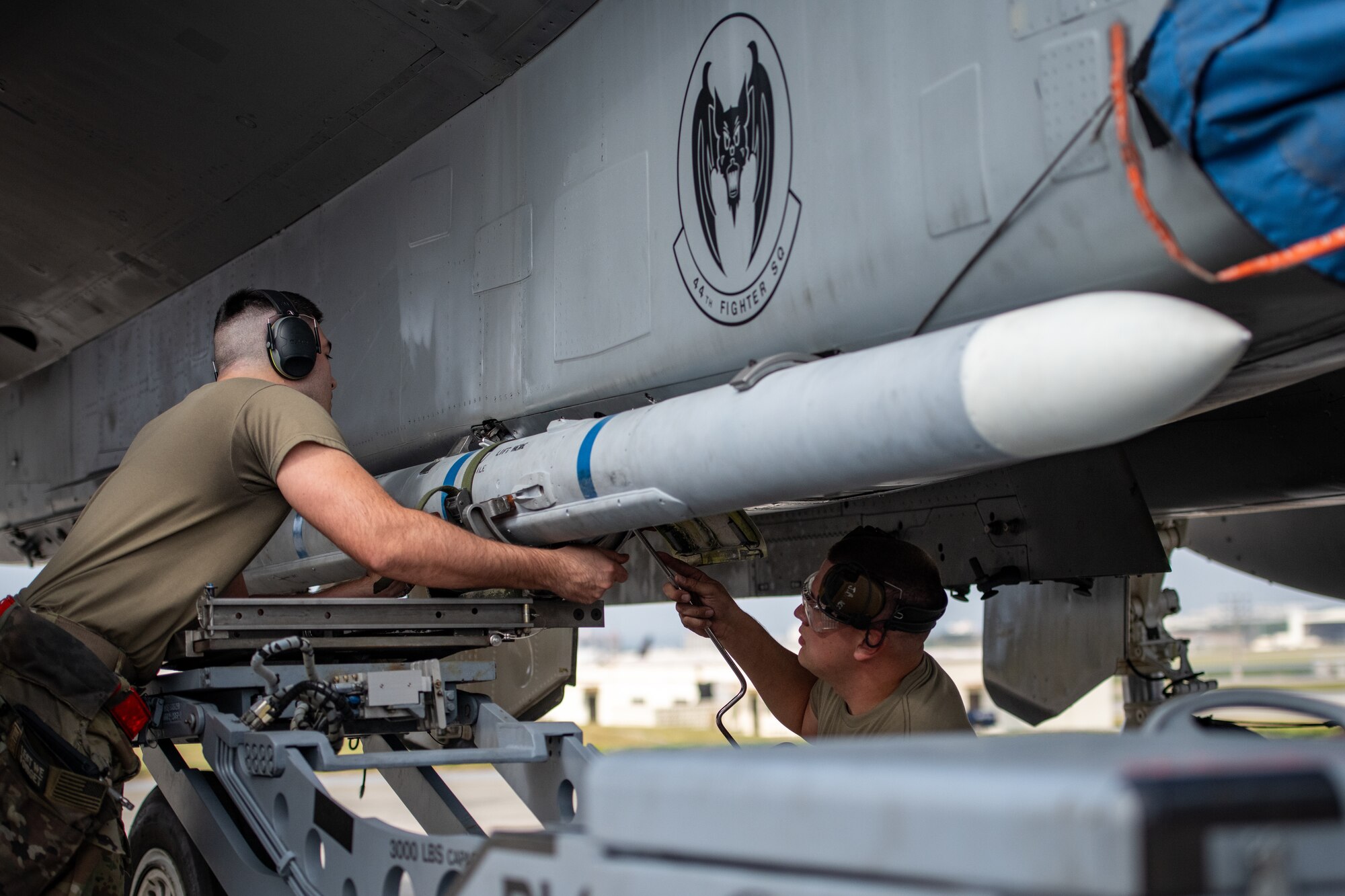 Airmen from the 18th Aircraft Maintenance Squadron load an AIM-120 Advanced Medium Range Air-to-Air Missile onto an F-15C Eagle during a weapons load competition at Kadena Air Base, Japan, Nov. 17, 2023. The competition pitted Active Duty and Air National Guard Airmen from three squadrons against each other to determine the finest weapons load team at the Keystone of the Pacific. (U.S. Air Force Photo by Lt. Col. Raymond Geoffroy)
