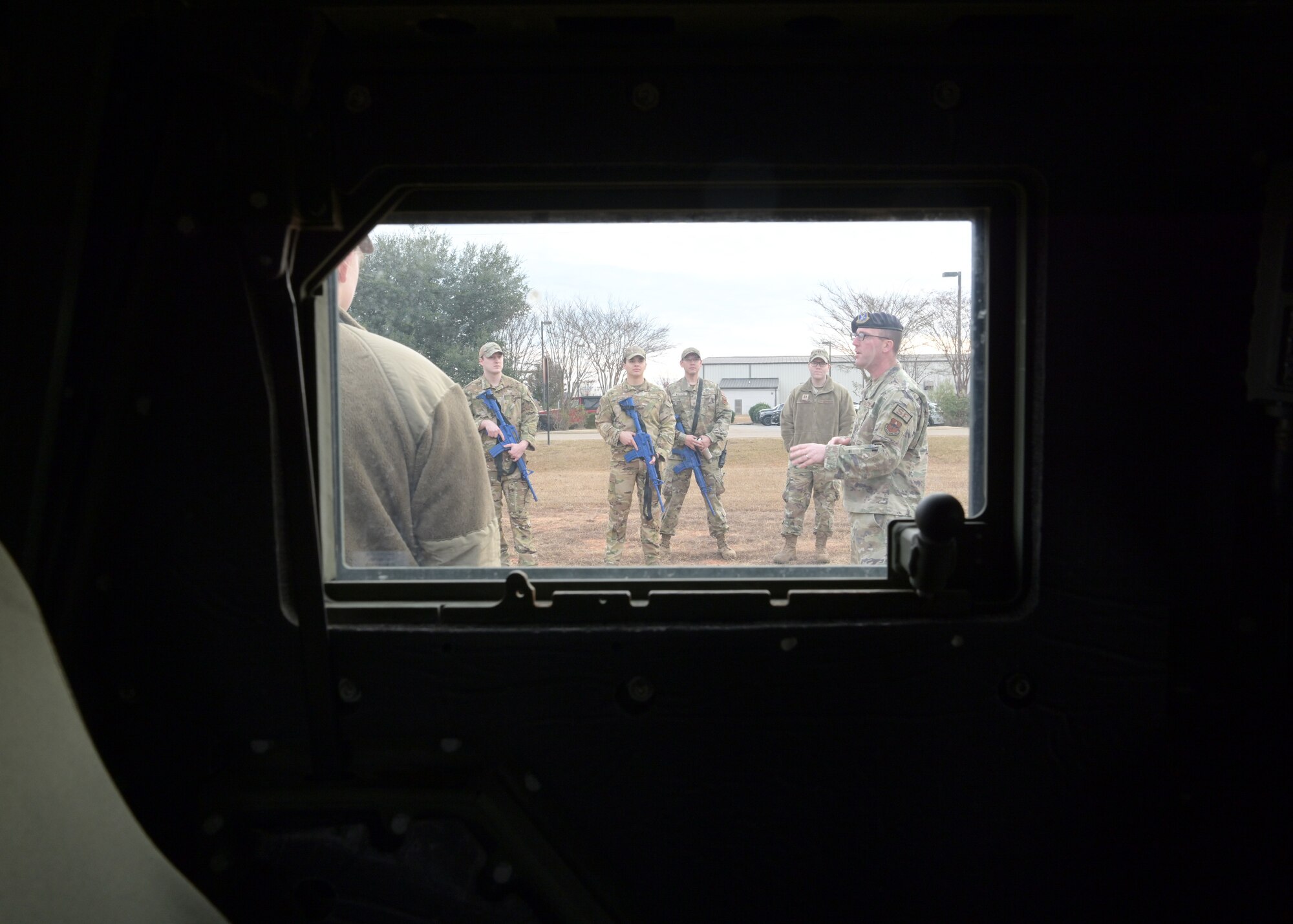 A group of Airmen are seen through the window of a vehicle.