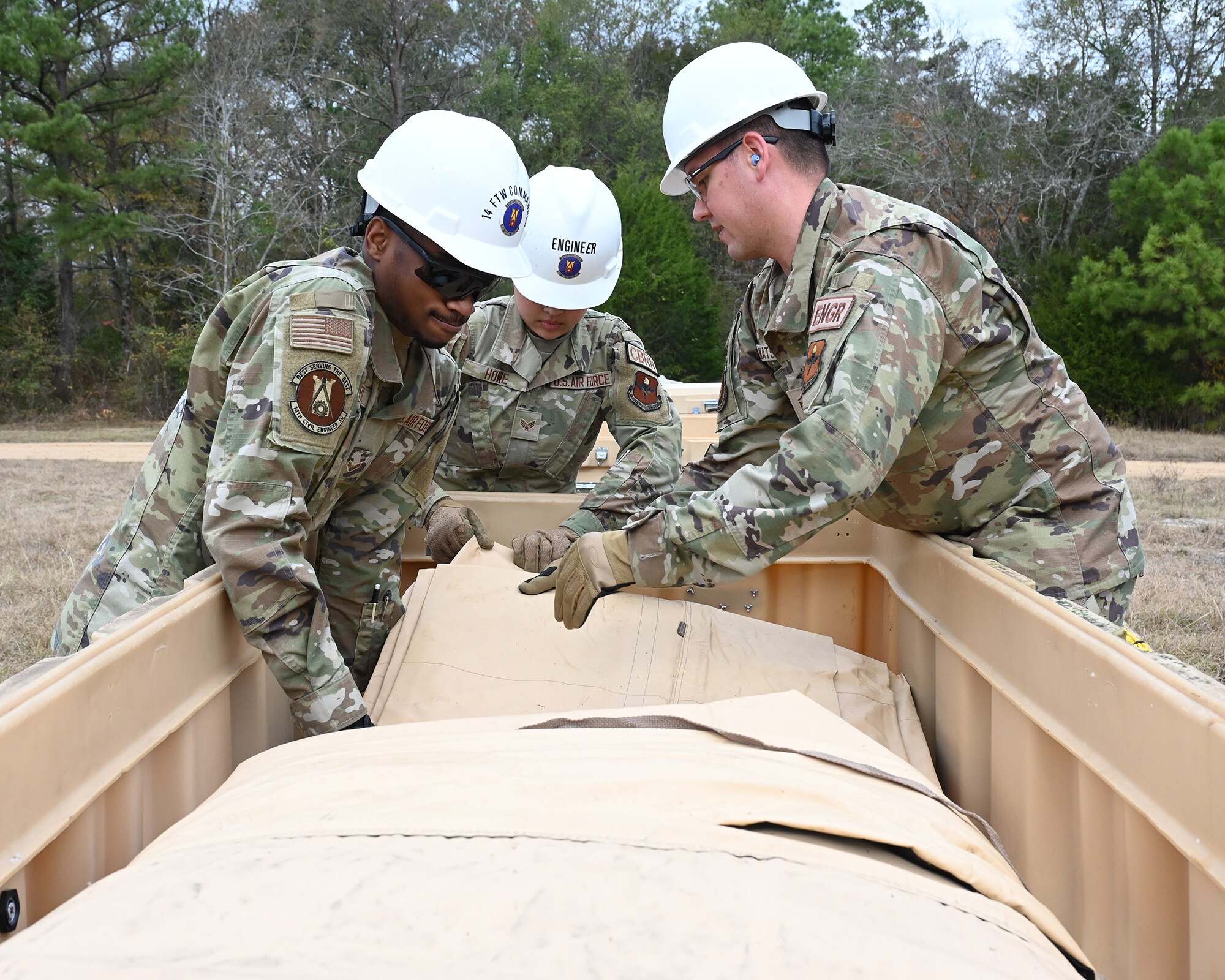 A group of Airmen unpack a large tent.