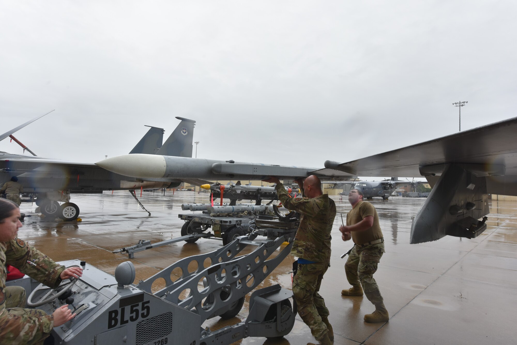 Three Airman load a bomb onto an aircraft