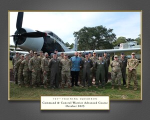 photo of 21 military members and civilians standing outside in from of an airplane in an air park museum.