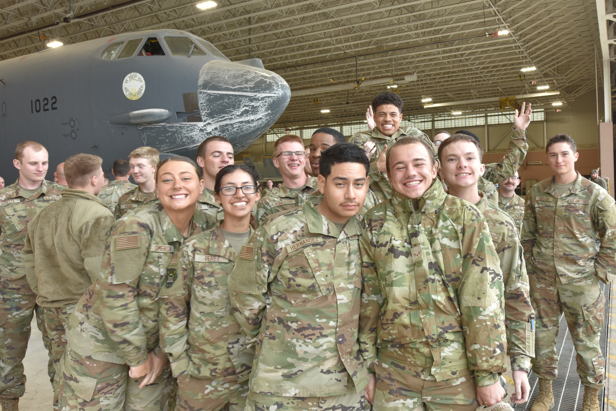 A group of Airmen smile at the camera inside a hangar.