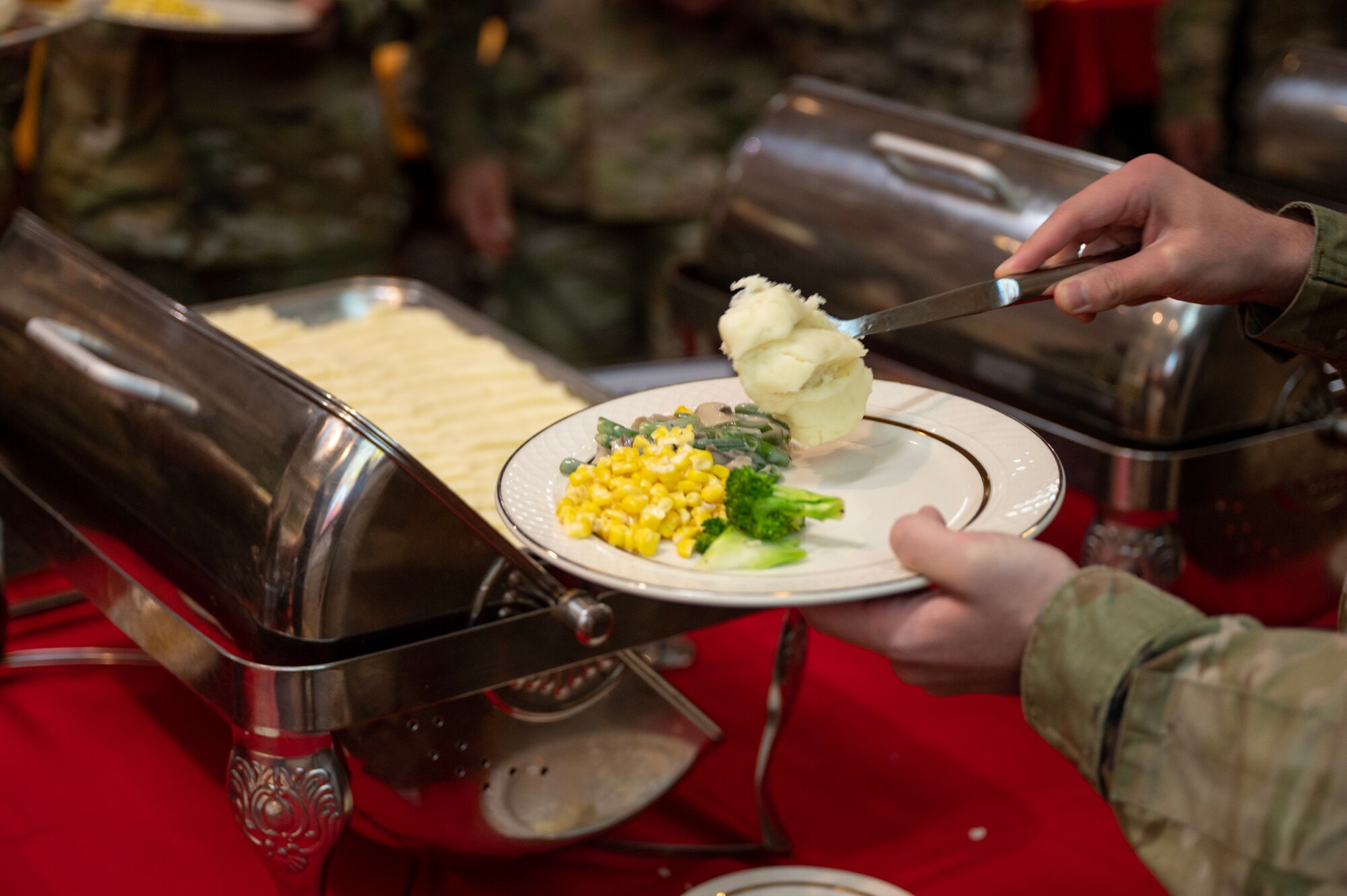 A U.S. Air Force Airman assigned to the 8th Fighter Wing, Kunsan Air Base, Republic of Korea, scoops food onto a plate during the annual Thanksgiving meal hosted by the Korean-American Gunsan Alliance.