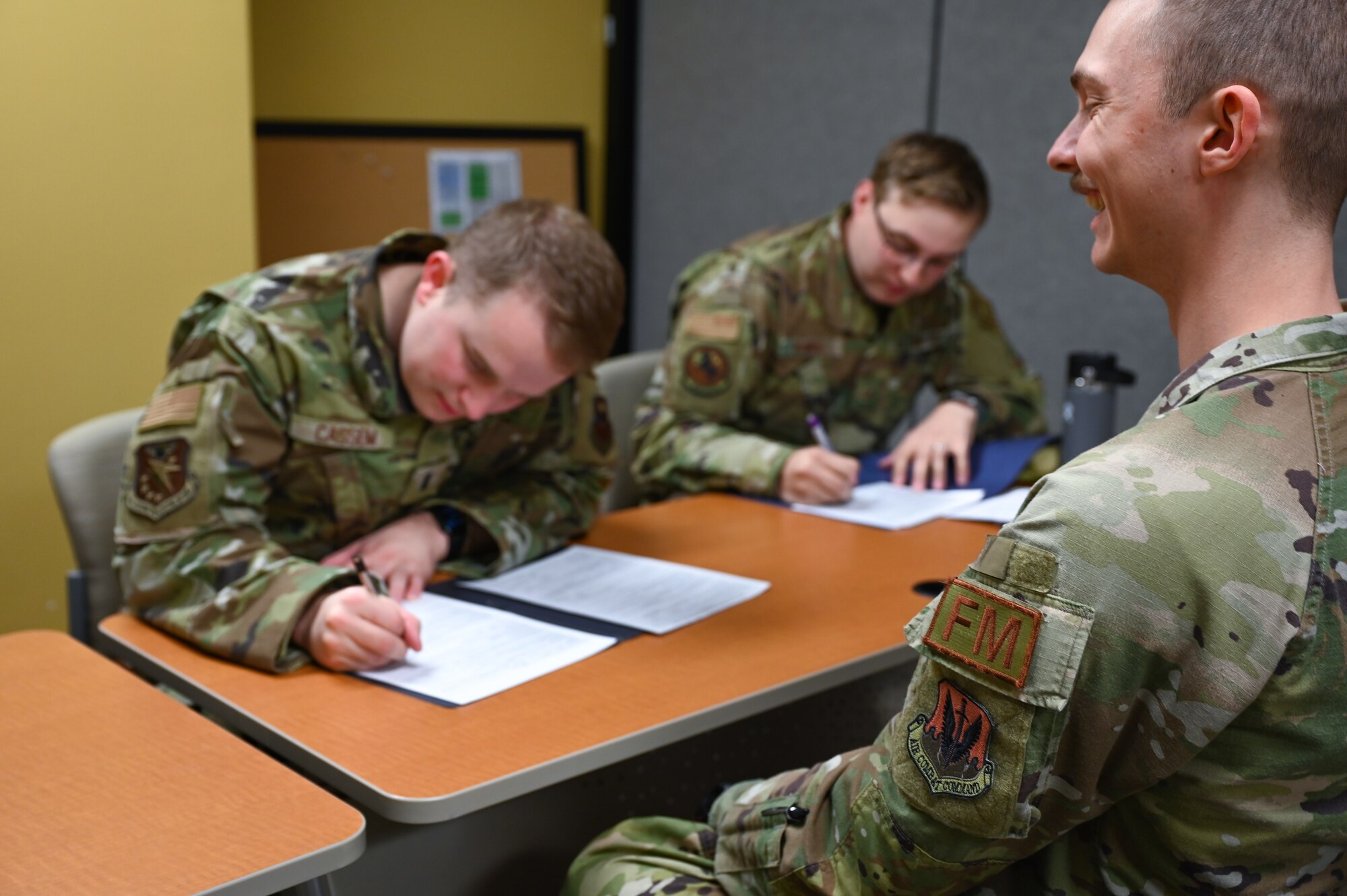 Airmen writing down information in front of a financial operations technician for in-processing
