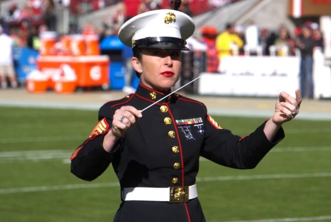 Female Marine in uniform conducts band during performance at San Francisco 49ers football game