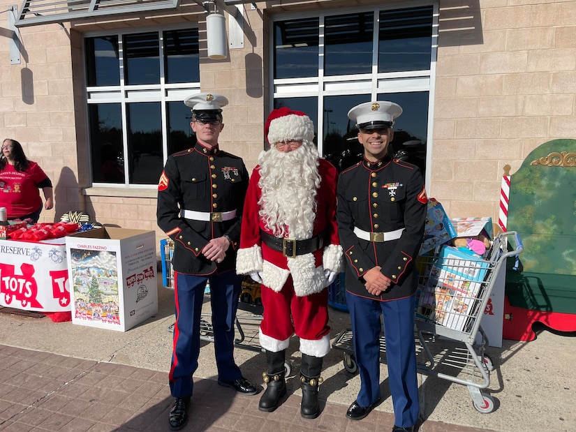 Two Marines in dress uniform pose for a photo with Santa.