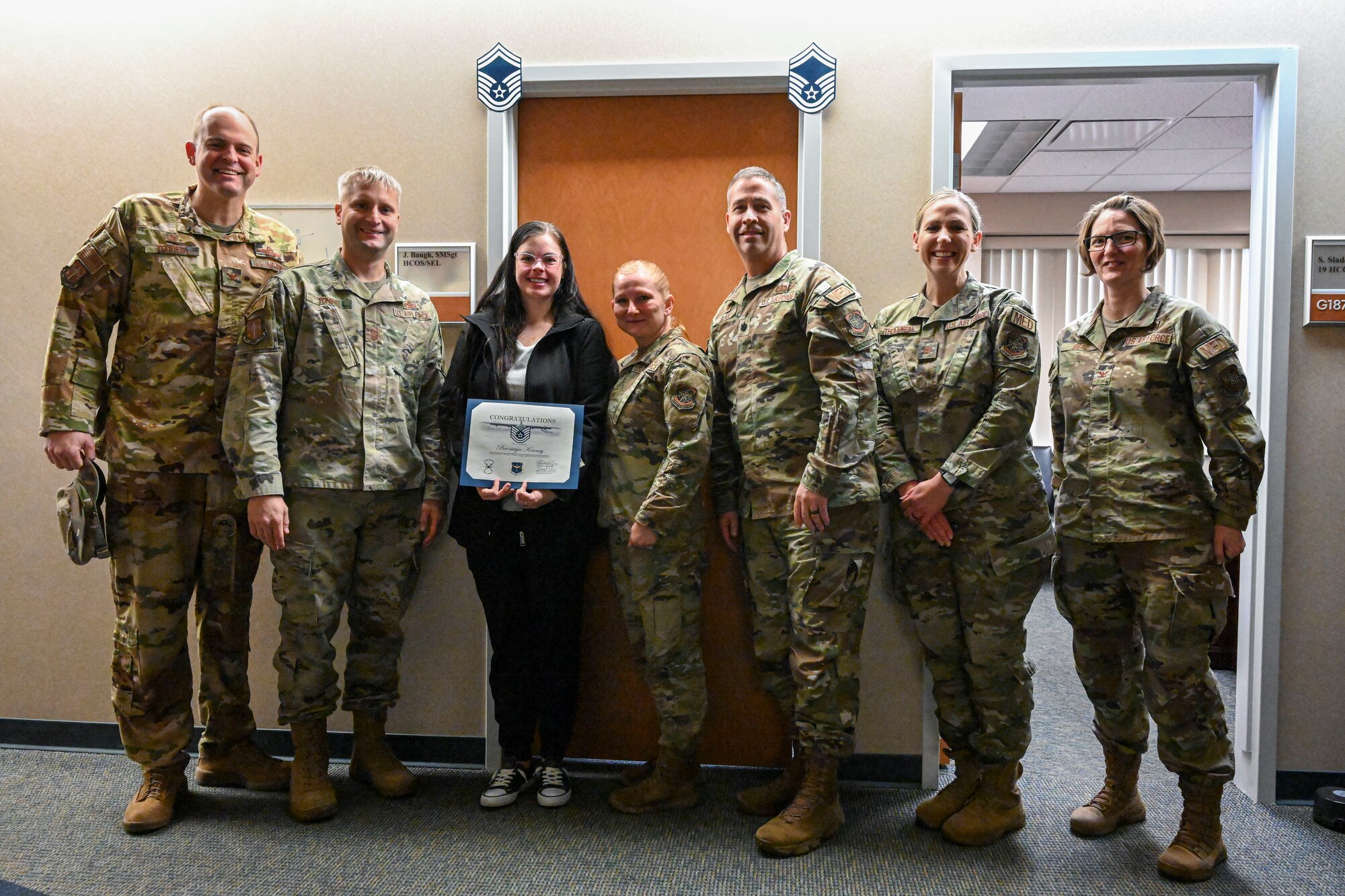 Leadership from the 19th Airlift Wing and the 19th Medical Group pose for photo with Staff Sgt. Bronwyn Kenney during a surprise Stripes for Exceptional Performers promotion