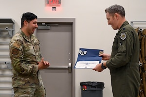 Lt. Col. Jonathan Feucht, 19th Operations Support Squadron commander, presents Senior Airman Cesar Perez with a certificate for a Stripes for Exceptional Performers promotion