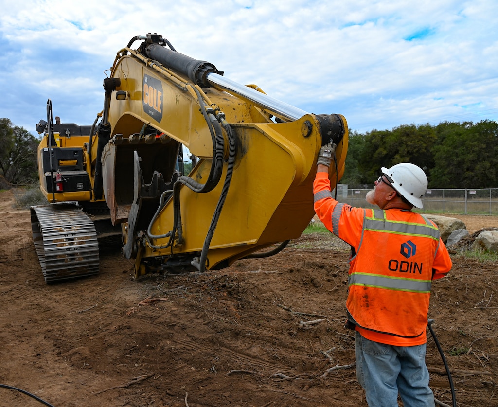 A man in construction gear checks the boom of a dozer for correct operation