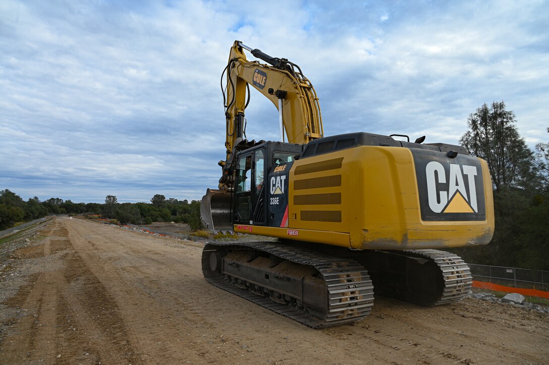 A dozer drives down a raised earthen dike