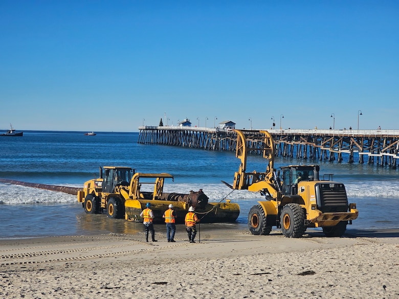 Crews check over placement of  sand pipeline at San Clemente  Pier