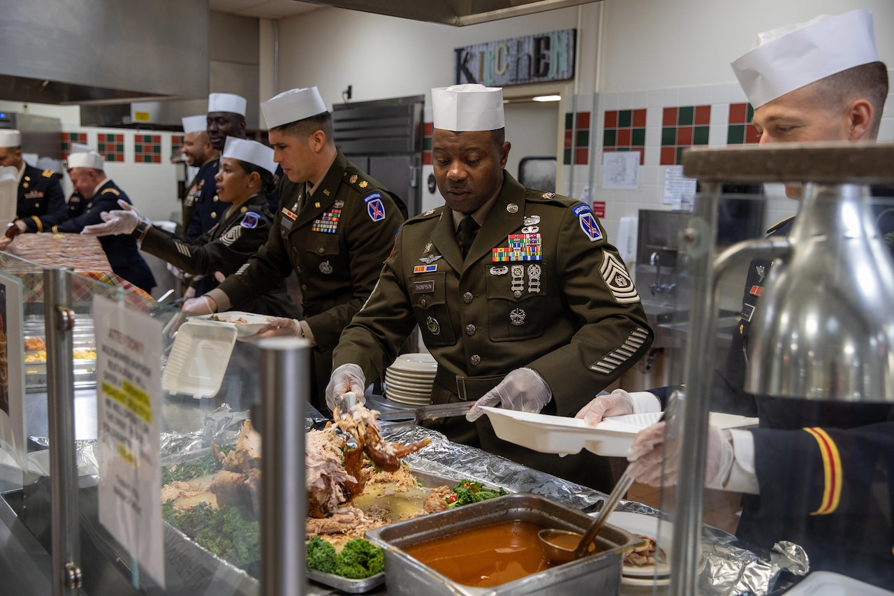 Service members serve food to fellow comrades.