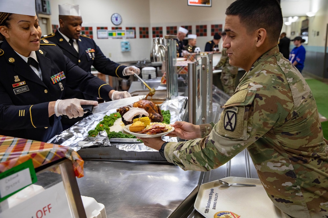 Service members serve food to fellow comrades.