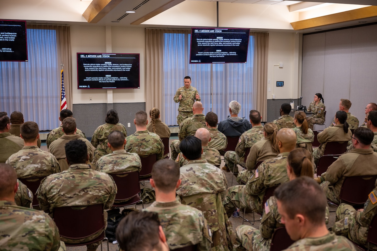 service members gather in a room to listen to a service member speak