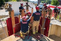 Members of the 911th Technical Rescue Engineer Company in both Army green fatigues and dark blue t-shirts are standing around a mock trench learning how to rescue someone from below.