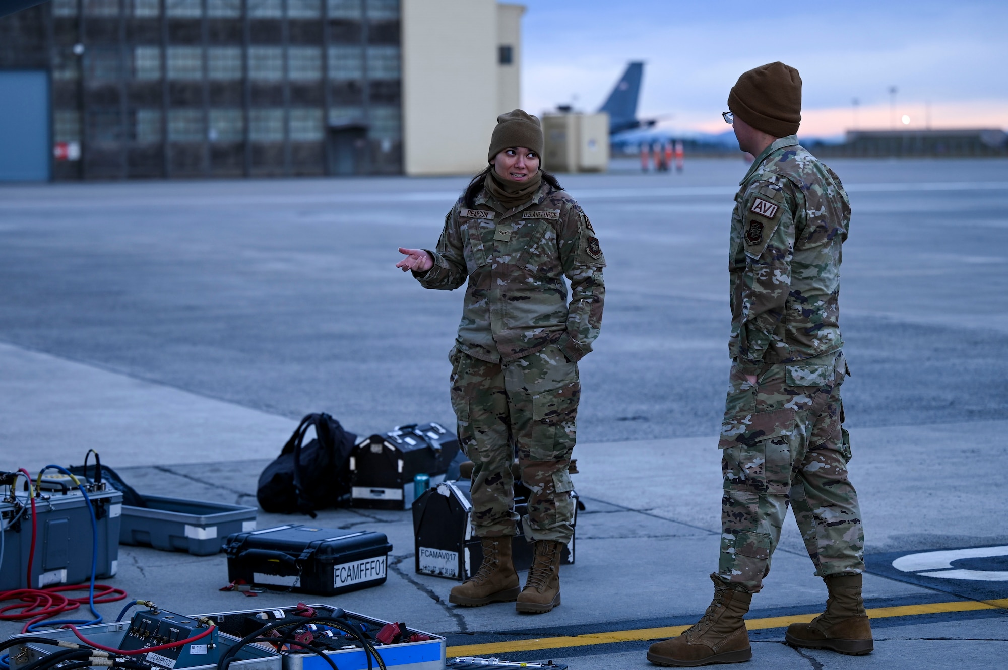 Airmen talk in front of an aircraft on the flightline.