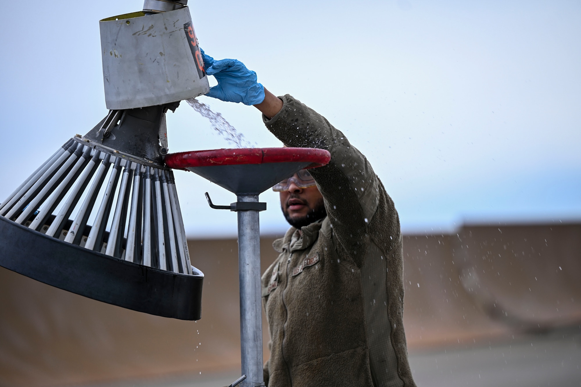 An Airman drains fuel out of a drogue.