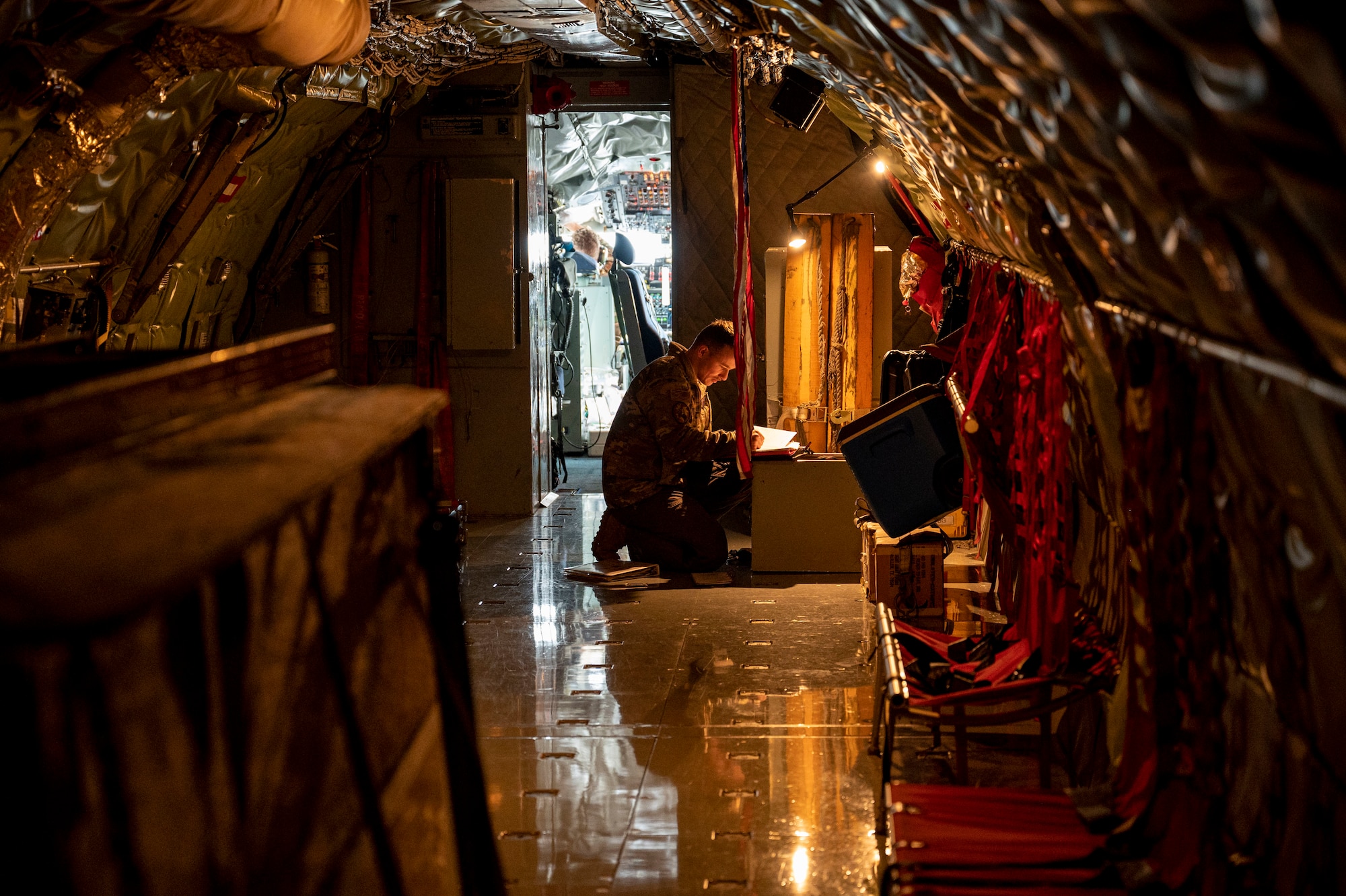 An Airman reads papers on an airplane.