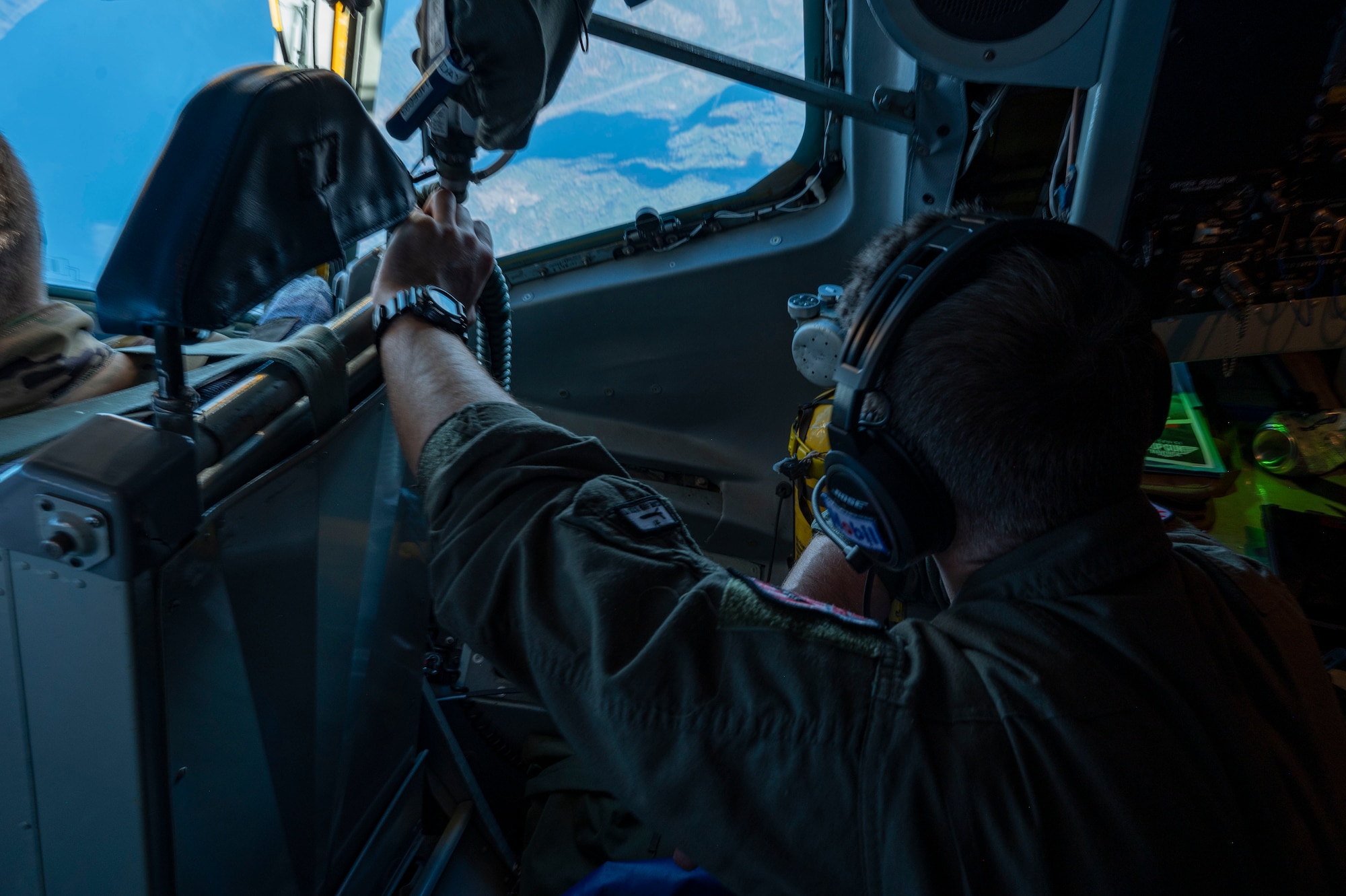 An Airman looks out the window of a plane.