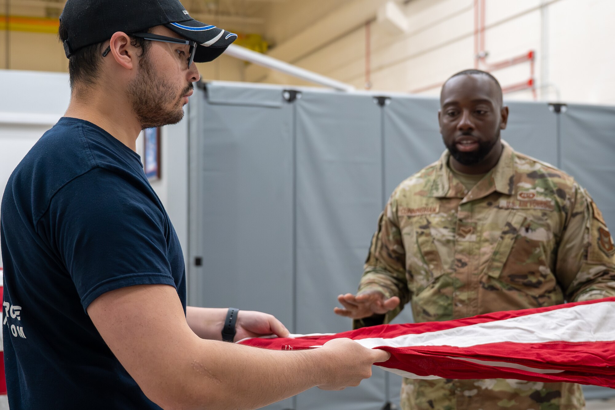 Airman 1st Class Matthew Sharp and Senior Airman Latavious Cunningham, members of the Air Force Honor Guard, fold a U.S. flag during a practice session on Nov. 14, 2023, at Homestead Air Reserve Base, Fla. Sharp's active participation in this session signifies his remarkable journey of recovery and the support he has received from his fellow Airmen. (U.S. Air Force photo by Tech. Sgt. Lionel Castellano)