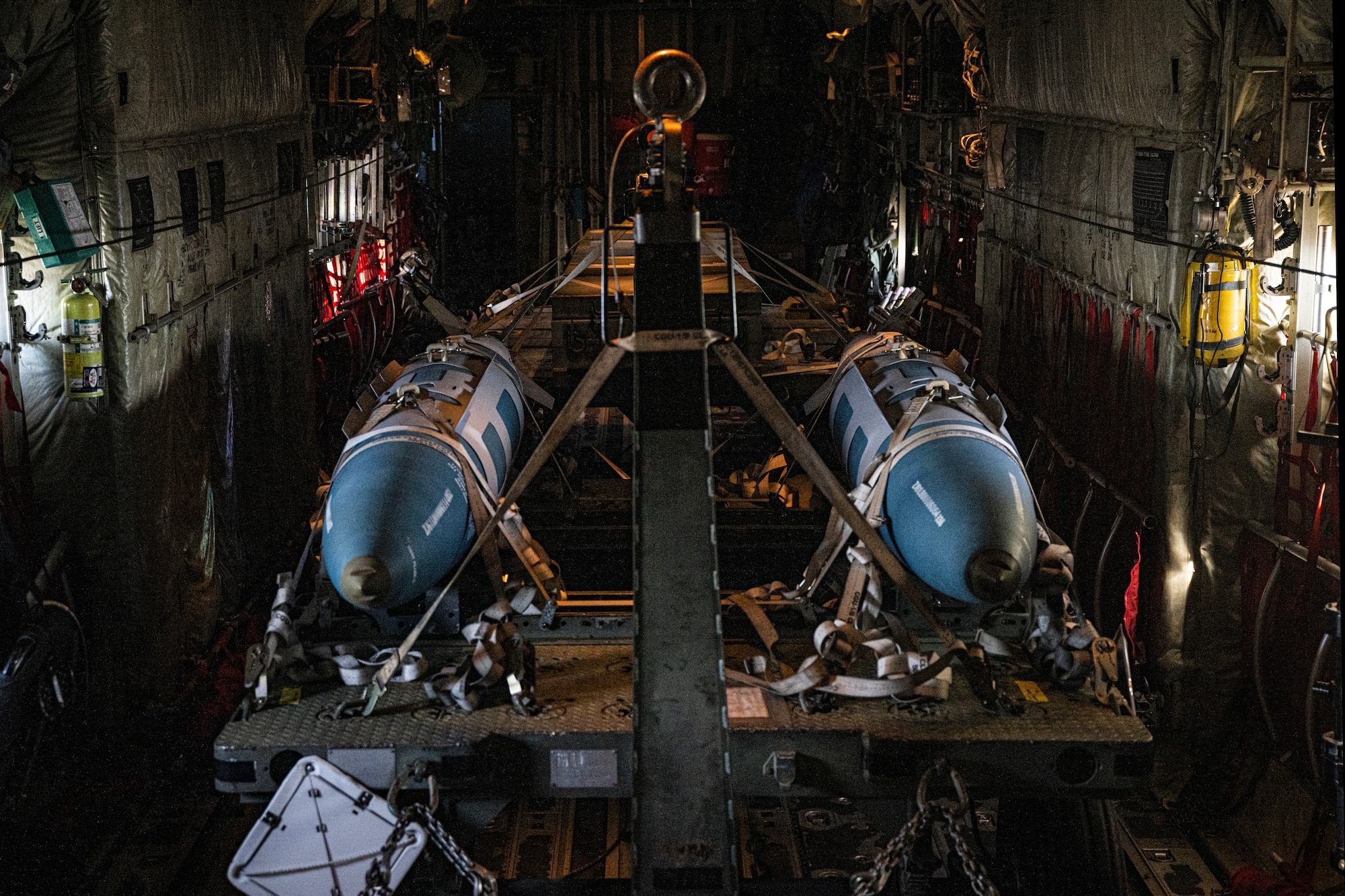 Two inert training bombs sit on a trailer inside a U.S. Air Force C-130J Super Hercules, assigned to the 19th Airlift Wing, Little Rock Air Force Base, Arkansas, flying over the Eastern United States, Nov. 14, 2023, for Exercise Razor Talon 24-1. RT-24 is an agile combat employment focused exercise, designed to test the 4th Fighter Wing's ability to operate as a lead wing to generate combat airpower while continuing to move, maneuver, sustain the wing and subordinate force elements in a dynamic contested environment. (U.S. Air Force photo by Staff Sgt. Devin M. Rumbaugh)