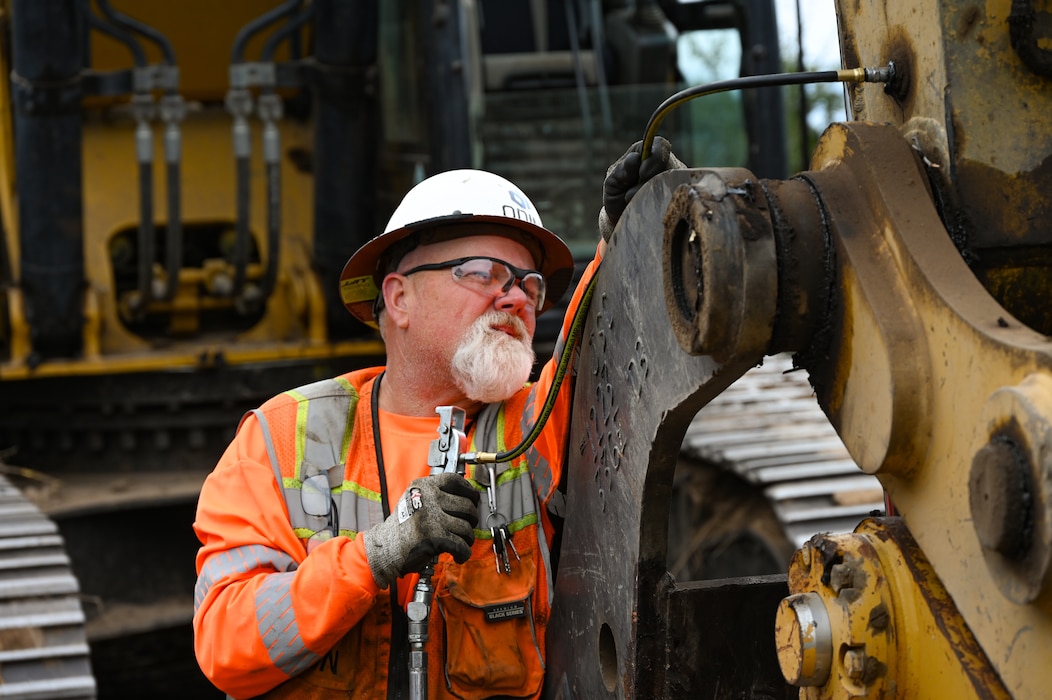 A man in construction gear checks the boom of a dozer for correct operation.