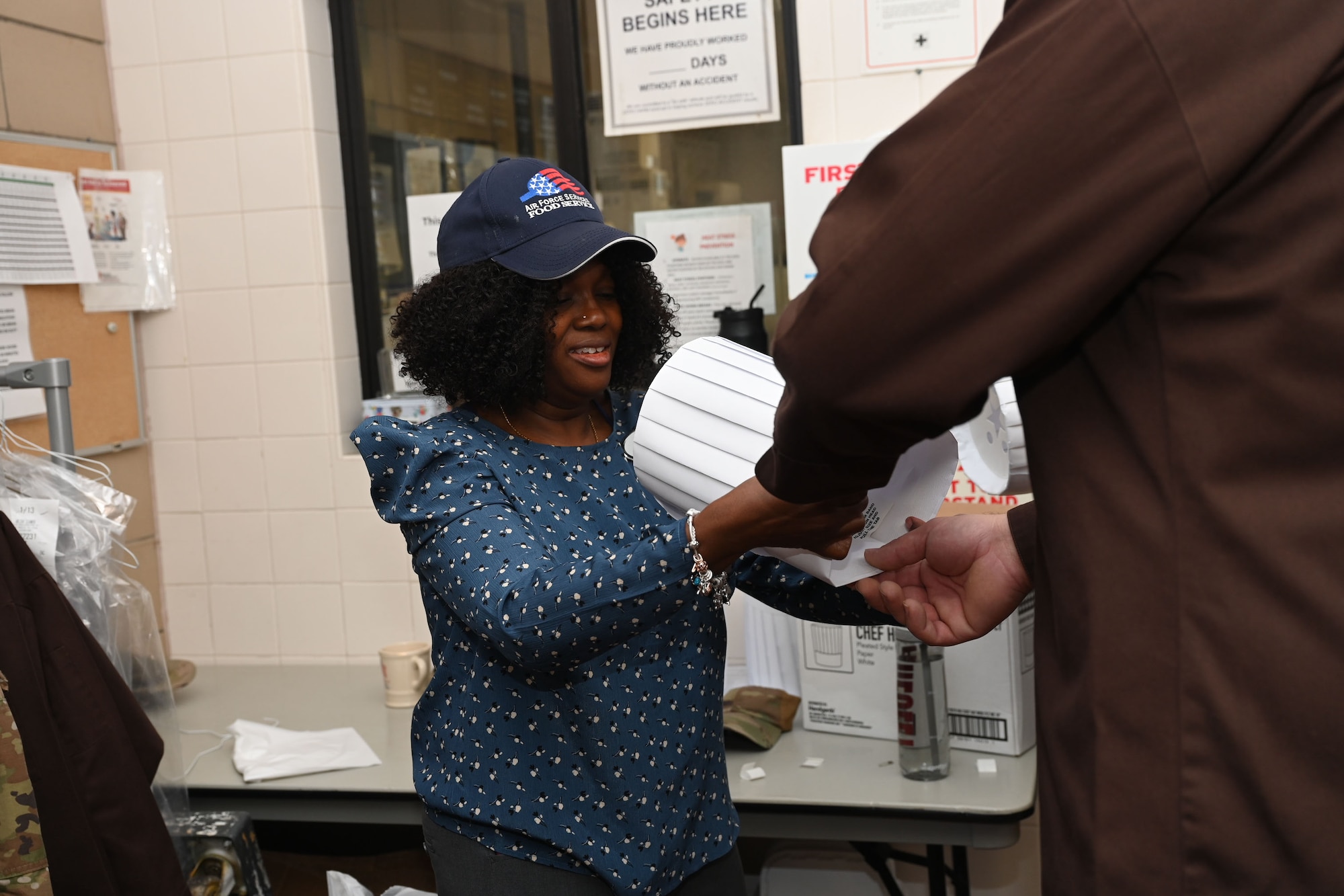 Ms. Keisha Singletary, Western Winds Dining Facility food operations manager, prepares volunteers to serve lunch Thanksgiving day at the Western Winds Dining Facility, Goodfellow Air Force Base, Texas, Nov. 23, 2023. Volunteers had to wear a chef's coat and hat to adhere to the food safety regulations. (U.S. Air Force photo by Airman 1st Class Evelyn J. D’Errico)
