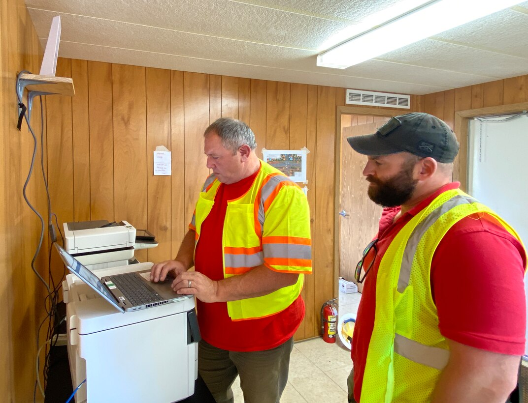 U.S. Army corps of Engineers CIO/G6 Enterprise Emergency Response Team members Dale Carton and Ryan Meersman complete set up and installation of printers and a WiFi router in a construction trailer at the site where a temporary elementary school is being built.