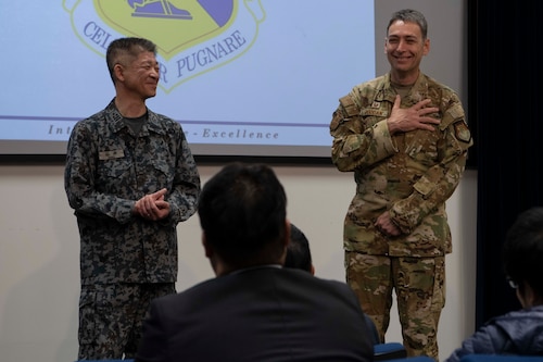 Two military men smile during a presentation.