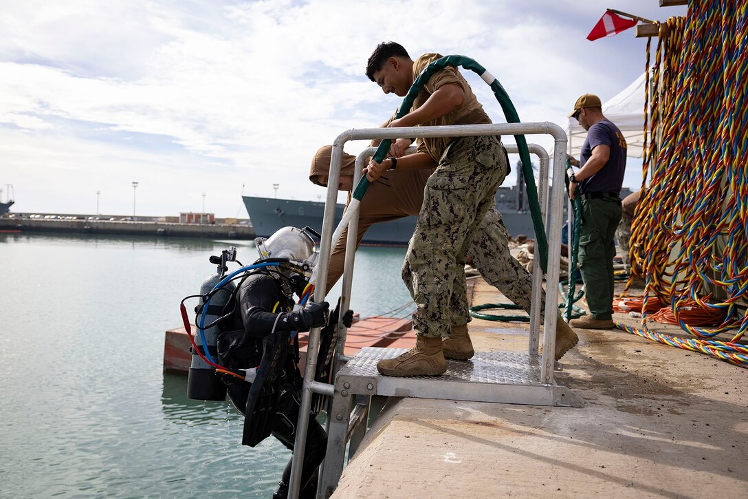 A sailor is helped back onto a pier after a dive.