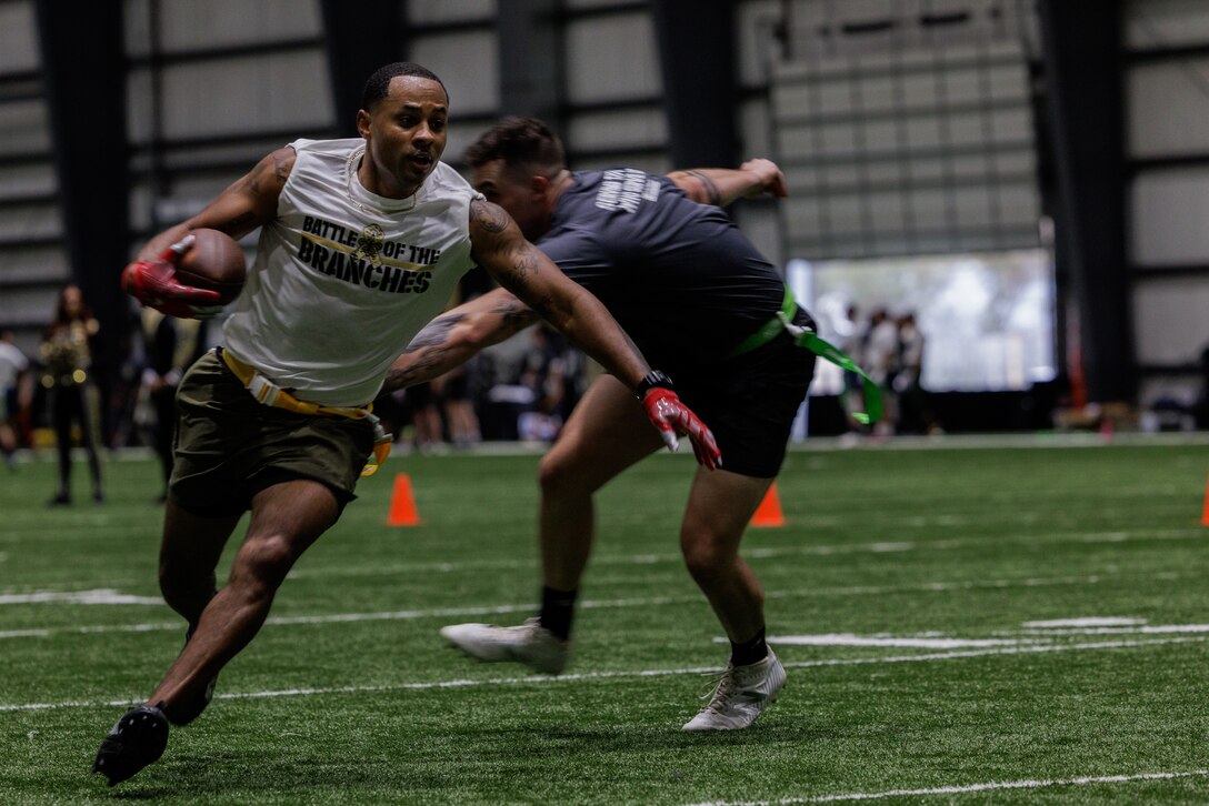 U.S. Marine Corps Master Sgt. Kevin Thompson, an equal opportunity representative with Headquarters Battalion, Marine Force Reserve, evades a defender during a flag football game during the Battle of the Branches tournament at the New Orleans Saints practice facility, Metairie, Louisiana, Nov. 21, 2023. Service members from each branch competed against each other in a physical fitness tournament hosted by the New Orleans Saints football team. The physical evaluations included a 40-yard dash, timed push-ups, tug of war, field goal kicking and distance throwing. (U.S. Marine Corps photo by Lance Cpl. Casey Cooper)