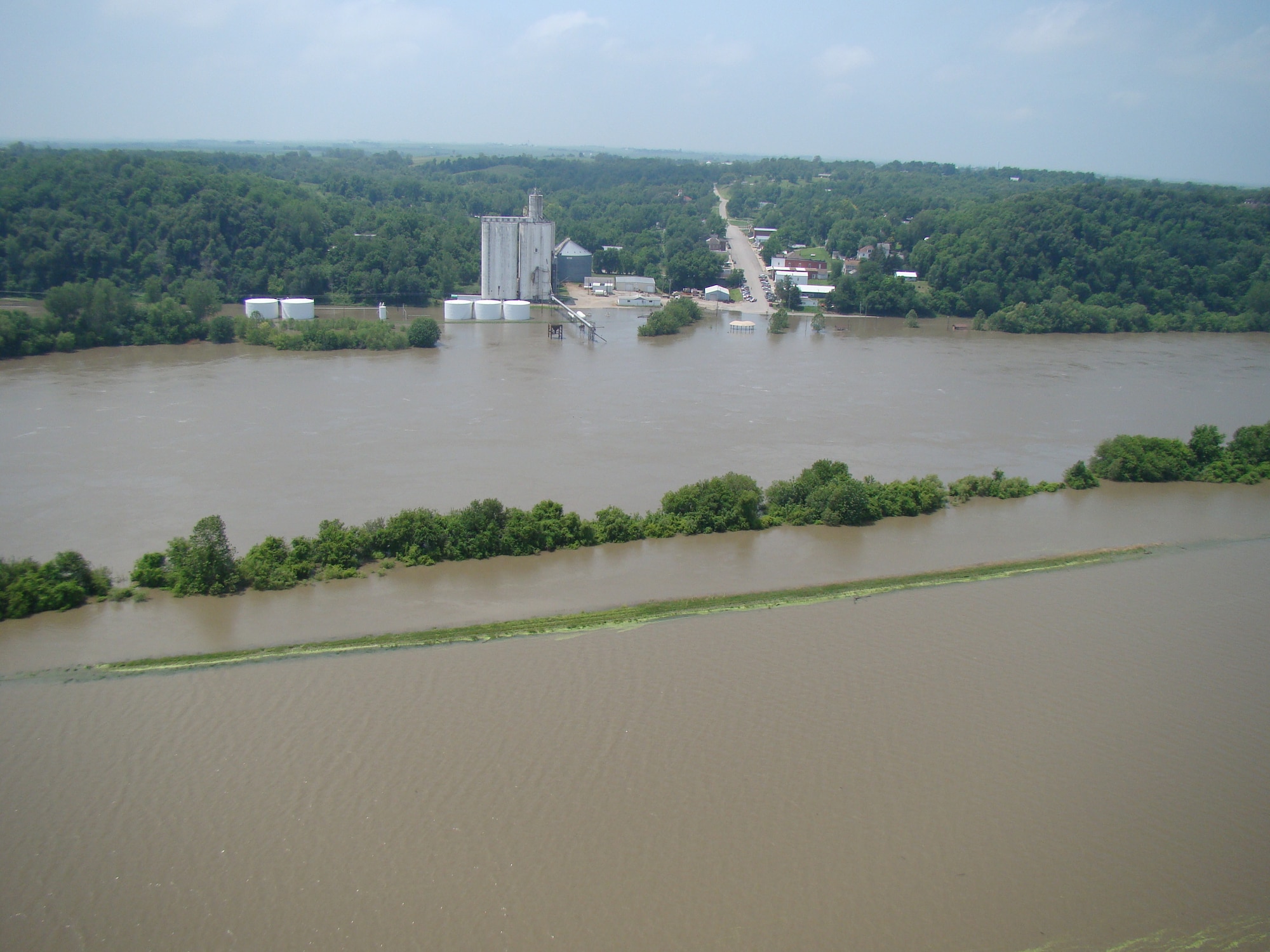 Brown water with trees and buildings in the background.