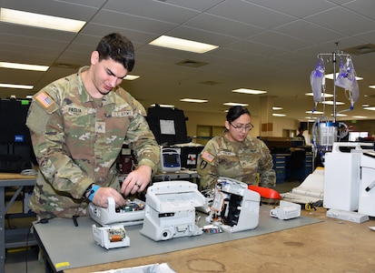 Sgt. Jason Paglia and Staff Sgt. Nora Martinez perform maintenance on patient monitors at the U.S. Army Medical Materiel Agency's Medical Maintenance Operations Division at Hill Air Force Base, Utah, Nov. 14, 2023.