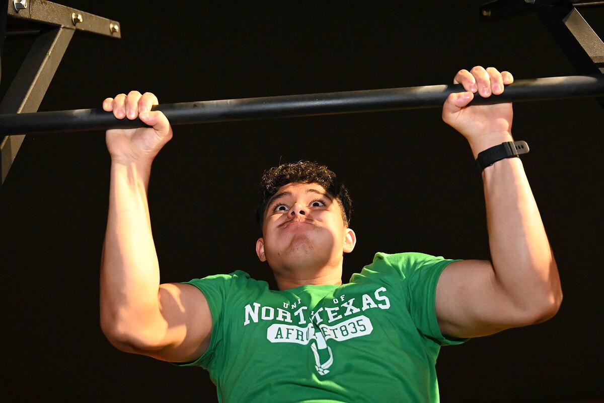 A cadet strains while pulling up on a bar.