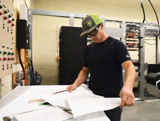 Man in hardhat examines electrical blueprint documents at Hydro Power Plant.