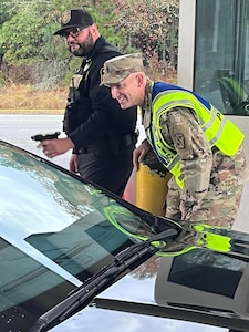 Command Sergeant Major Chuck Vaughn of 369th Signal Battalion greets drivers as part of the Leaders at the Gate initiative on Fort Eisenhower Nov. 18, 2023.