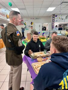 Command Sergeant Major Michael Starrett speaks to Advanced Individual Training Soldiers as they eat a Thanksgiving meal at a Warrior Restaurant on Post.