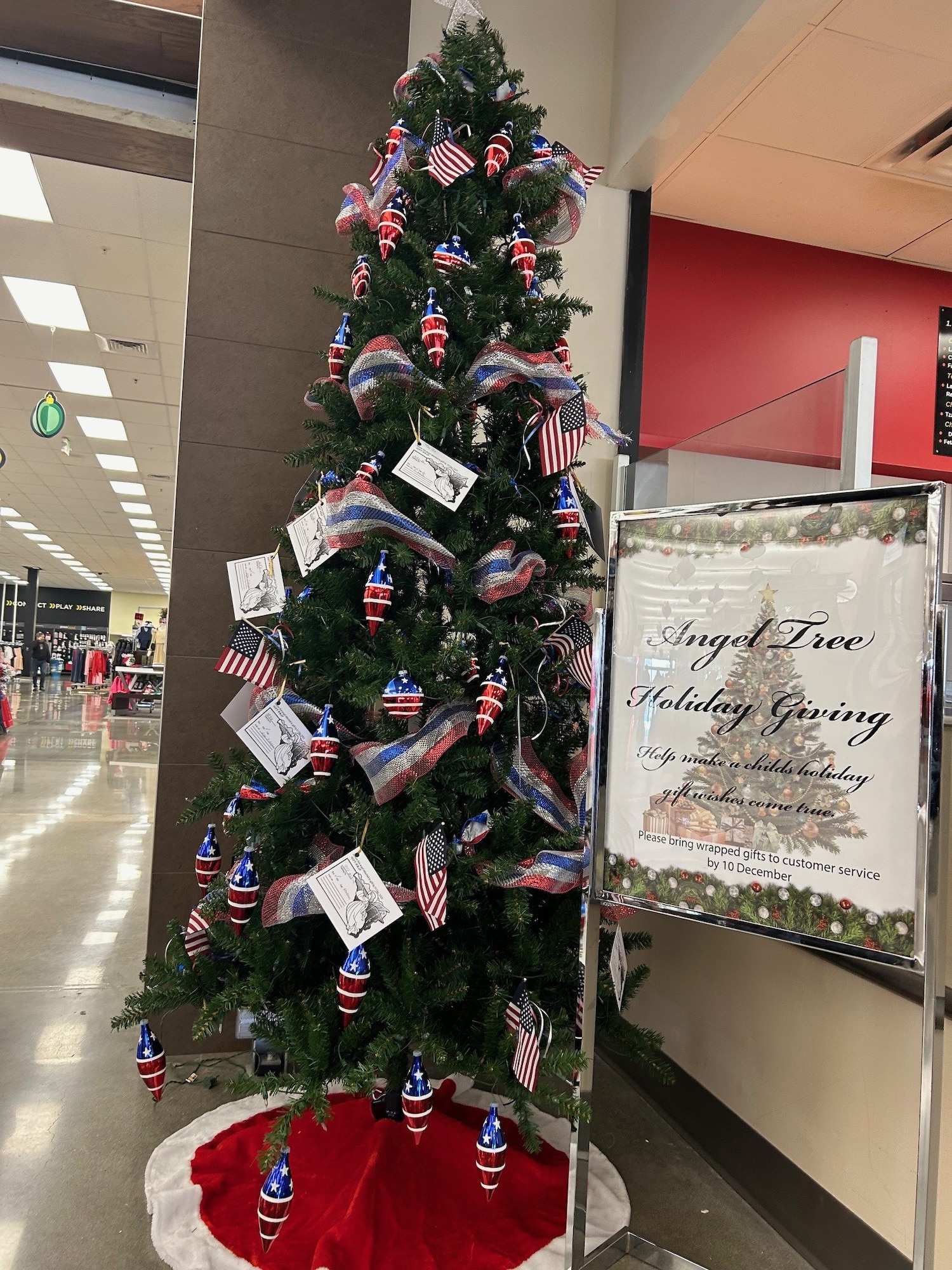 An artificial tree decorated in patriotic colors and flags with paper angels.